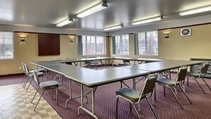 A conference room with a long table, chairs, a podium, and large windows. - Hôtel Le Portneuvois (Portneuf)