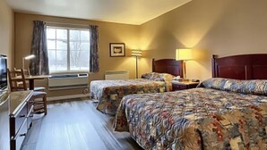 A hotel room with two beds, a desk, a chair, a television, and a window with curtains. - Hôtel Le Portneuvois (Portneuf)