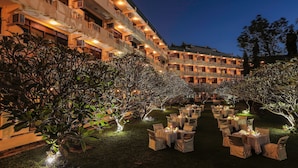 Un patio de hotel con asientos al aire libre y una fachada de edificio bien iluminada.