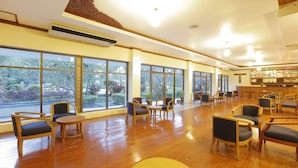 Un espacio interior amplio con ventanas grandes, piso de madera y varios arreglos de asientos.