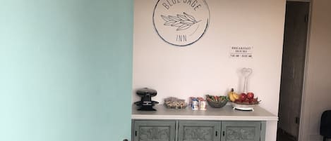 Et værelse med et skrivebord, et skilt på væggen med teksten "OFFICE" og et skilt, der angiver "Morgenmadsåbningstider 7:00 - 10:00".
