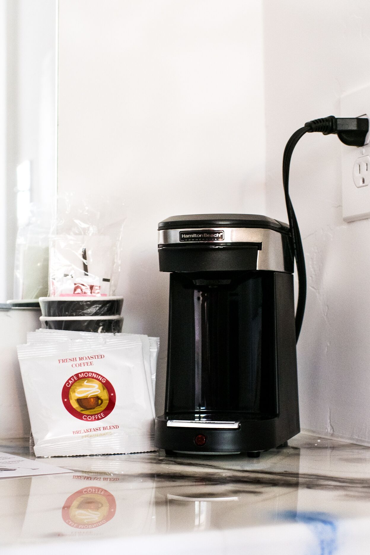 A coffee maker on a counter with a bag of fresh roasted coffee beside it.