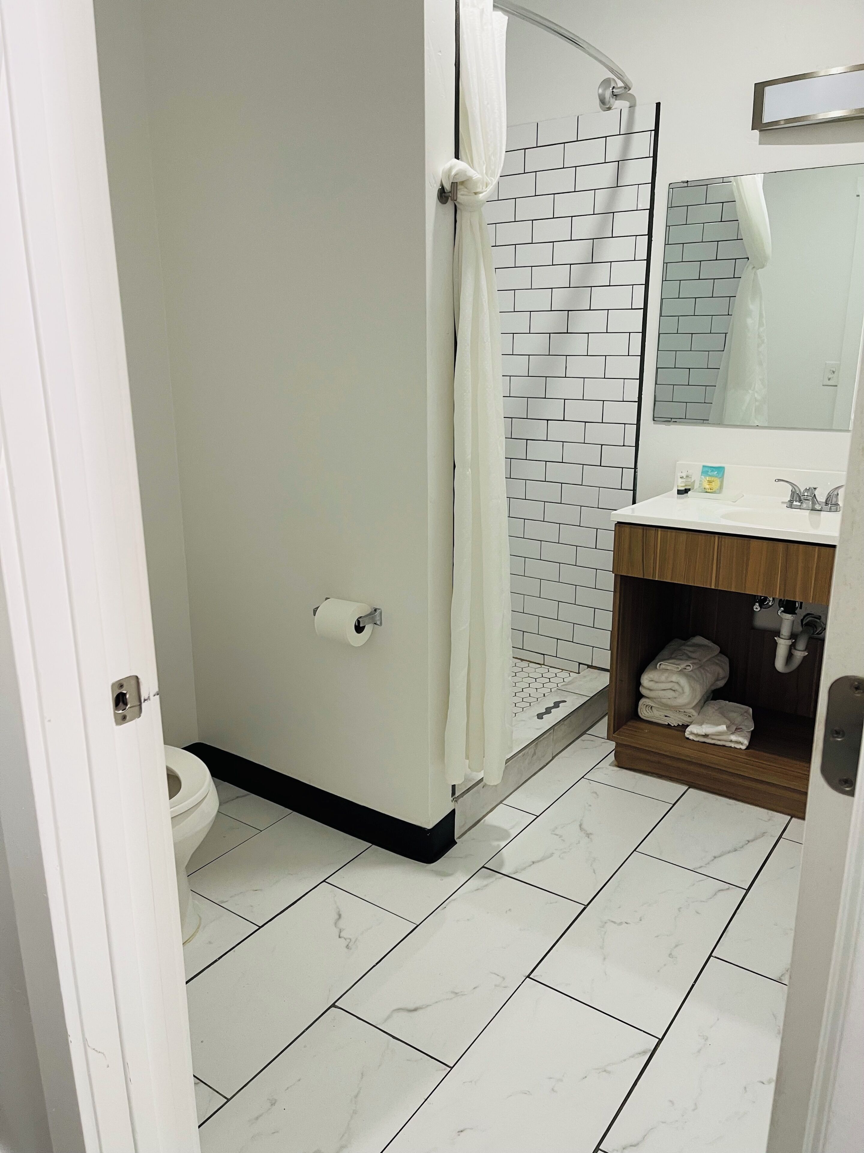 A bathroom with a toilet, shower, and sink.