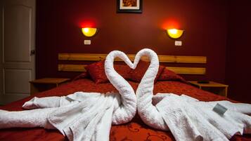 Habitación de hotel con cama, dos mesitas de noche y dos lámparas de pared.