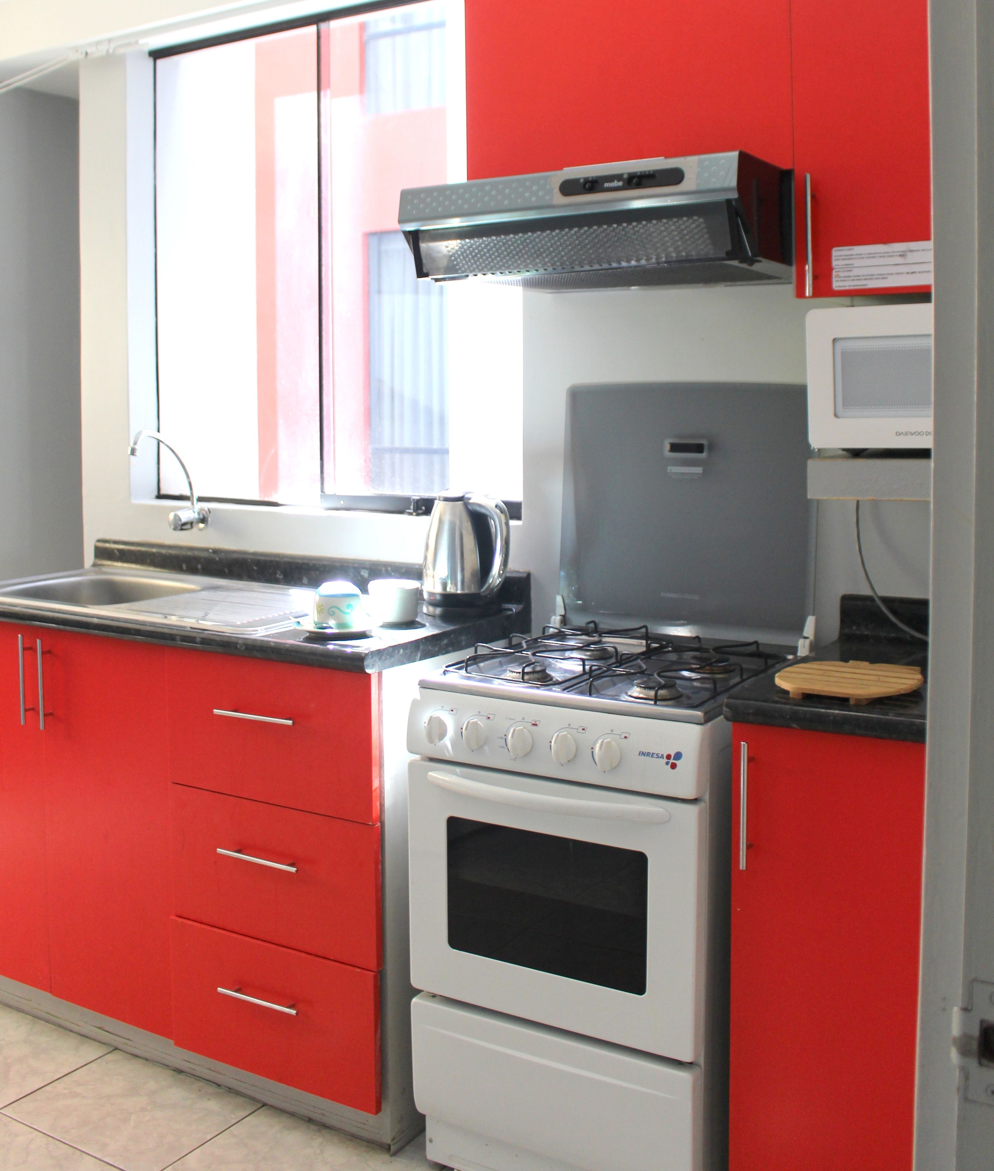 A kitchen with red cabinets, a white stove, and a microwave.