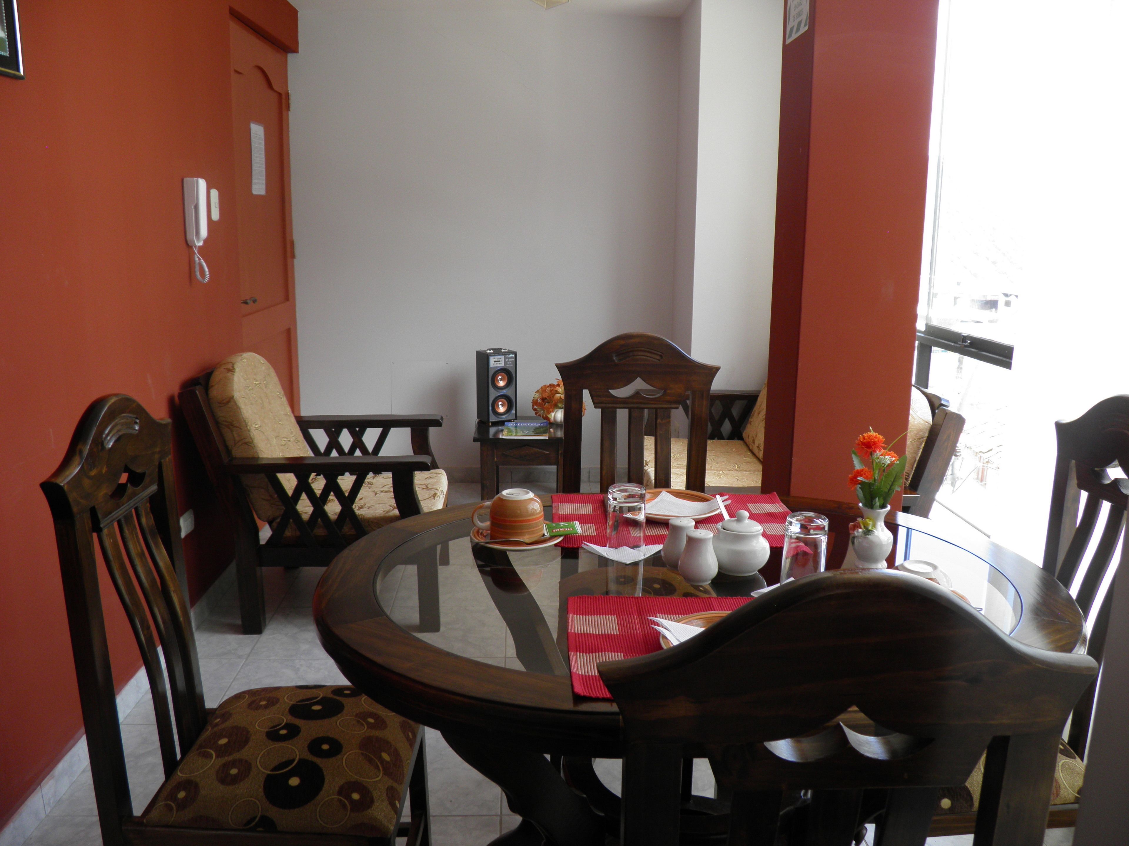 Een eethoek met een ronde tafel, stoelen en een rode placemat.