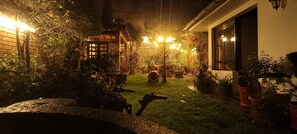 A well-lit outdoor area with a wooden pergola, potted plants, and a rustic outdoor seating area.