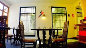 A dining area with a table and chairs, a bird decoration, and a window with a view. - Illas Inn (Cusco)