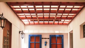 A hallway with a blue door, a wooden ceiling, and a tiled floor. - Illas Inn (Cusco)
