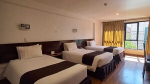 A hotel room with three beds, wooden flooring, a large window with curtains, and a view of greenery outside. - Illas Inn (Cusco)