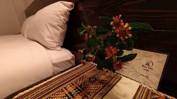 Una habitación de hotel con una cama, un tapete estampado y una planta con flores rojas.