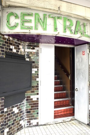 A building entrance with a sign reading "CENTRAL" and a staircase leading inside. - Trip Shot Hotels Koza (Okinawa)