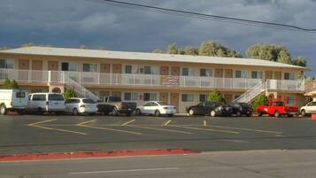 Un motel con struttura su due piani, un parcheggio con diverse auto e un balcone con ringhiera.