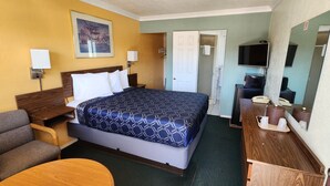 Habitación de hotel con una cama grande, un escritorio con computadora, un televisor y un cuadro en la pared.