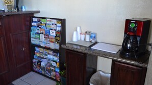 Una cocina con un refrigerador lleno de imanes, una cafetera y un cubo de basura.