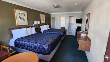 A hotel room with two beds, a desk, a chair, a television, and artwork on the walls.
