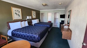 A hotel room with two beds, a desk, a chair, a television, and artwork on the walls.