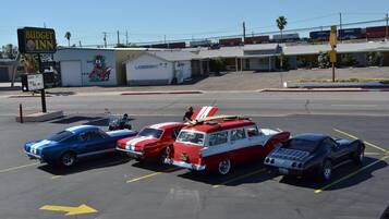 A parking lot with vintage cars, a laundromat, and a Budget Inn sign.