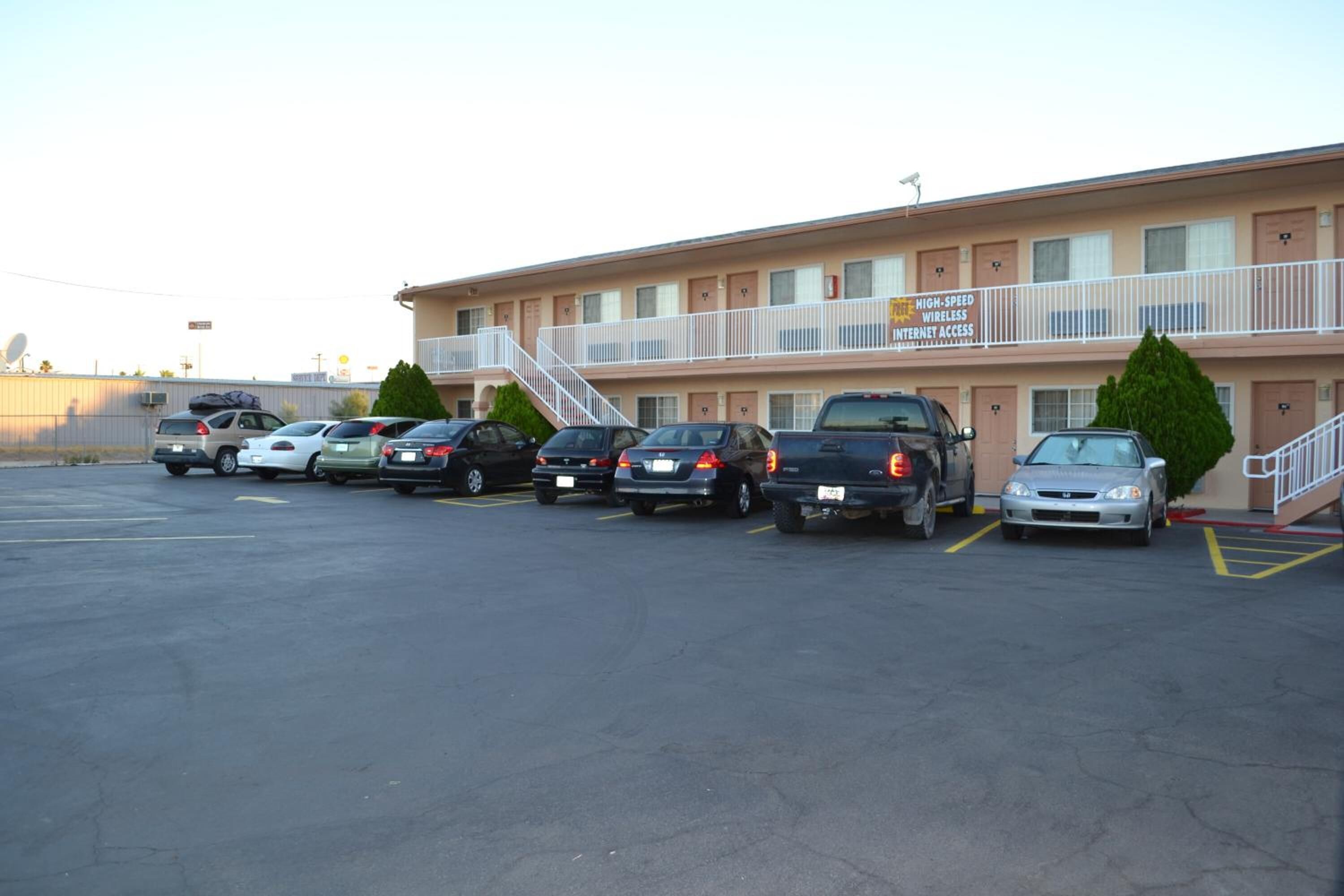 A motel with multiple parking spaces, a staircase to the upper level, and a sign indicating high-speed wireless internet access.