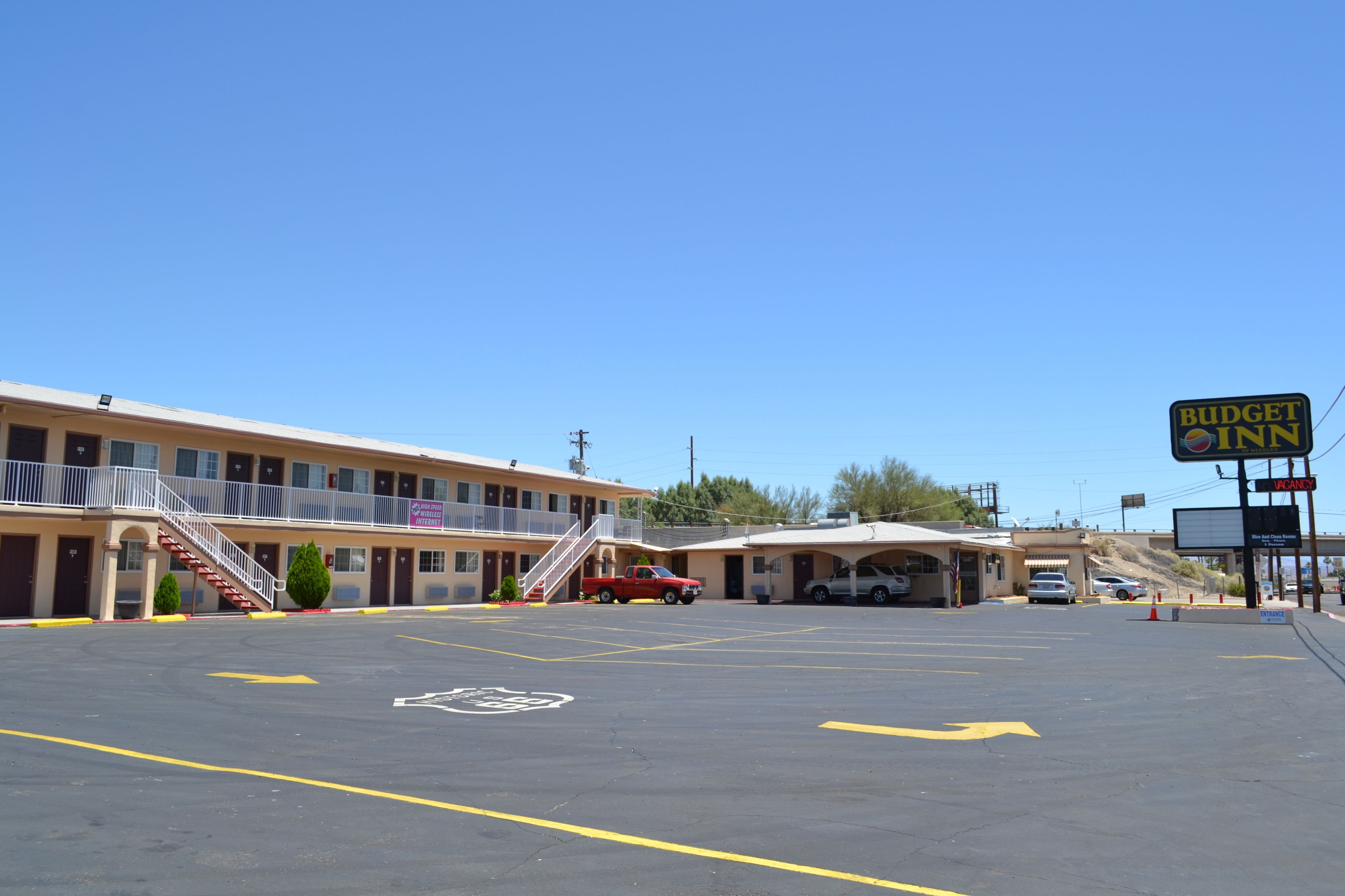 Un motel avec un parking, un camion rouge et une enseigne « Budget Inn ».