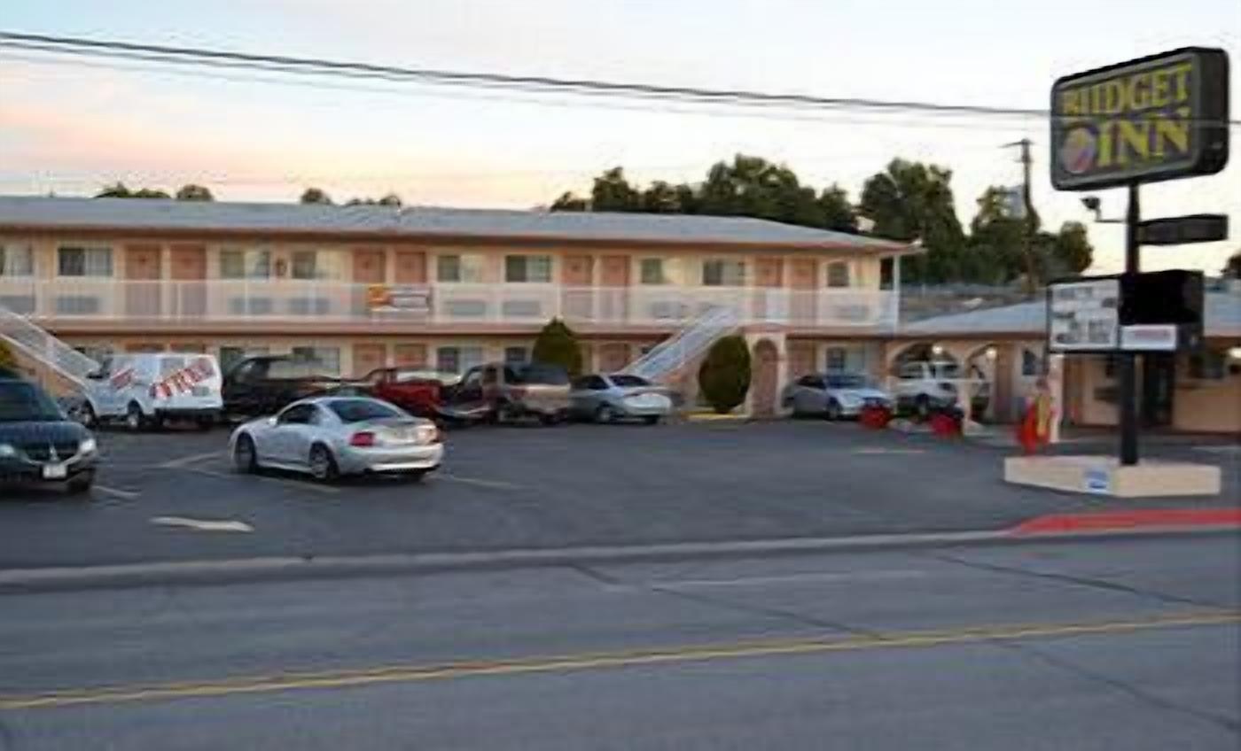 Un motel con aparcamiento, un cartel indicador y un edificio con varias ventanas.