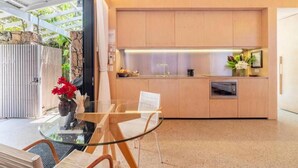 Una cocina moderna con armarios de madera, una mesa de comedor de vidrio y un horno empotrado.