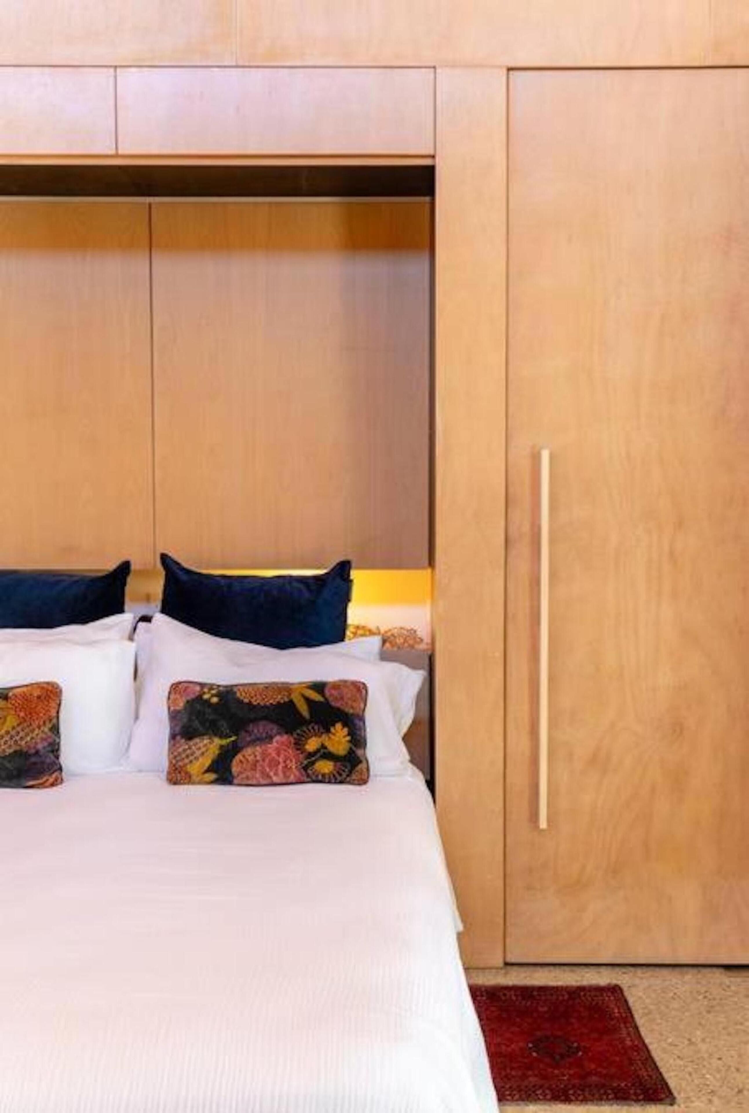 Un dormitorio con cama, almohadas y un armario.