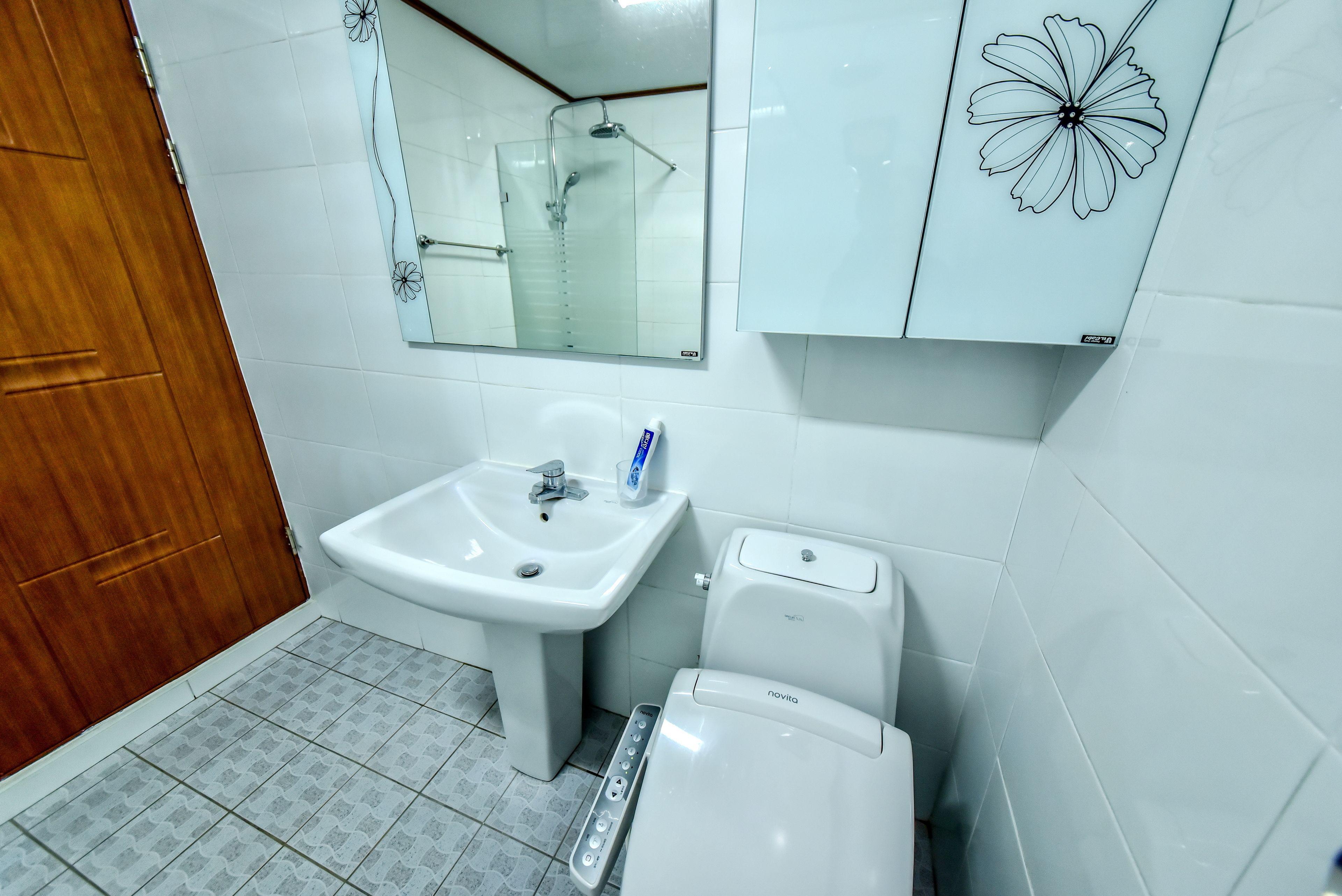A bathroom with a white sink, mirror, and toilet.