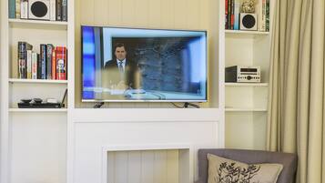 A living room with a television, bookshelves, a fireplace, a sofa, and a decorative vase.