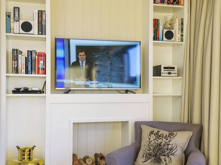 A living room with a television, bookshelves, a fireplace, a sofa, and a decorative vase.