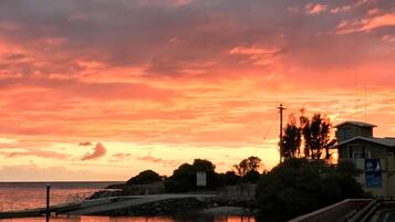 A sunset over a waterfront with a brick wall and wooden walkway.