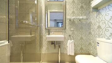 A bathroom with a glass shower enclosure, a sink with a mirror above it, and a toilet.