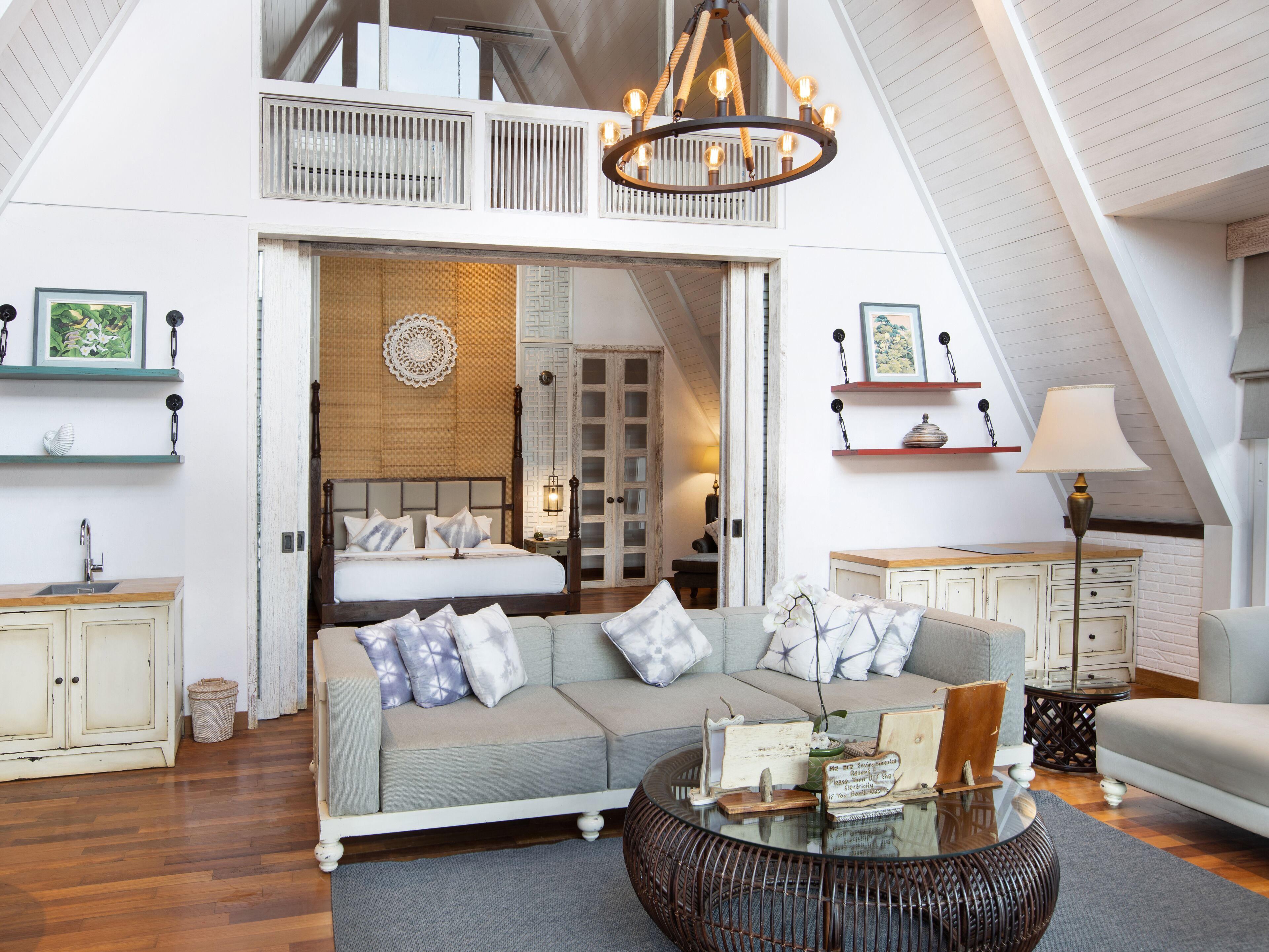 A spacious loft bedroom with a large bed, a sitting area with a sofa and coffee table, and a balcony with a view.
