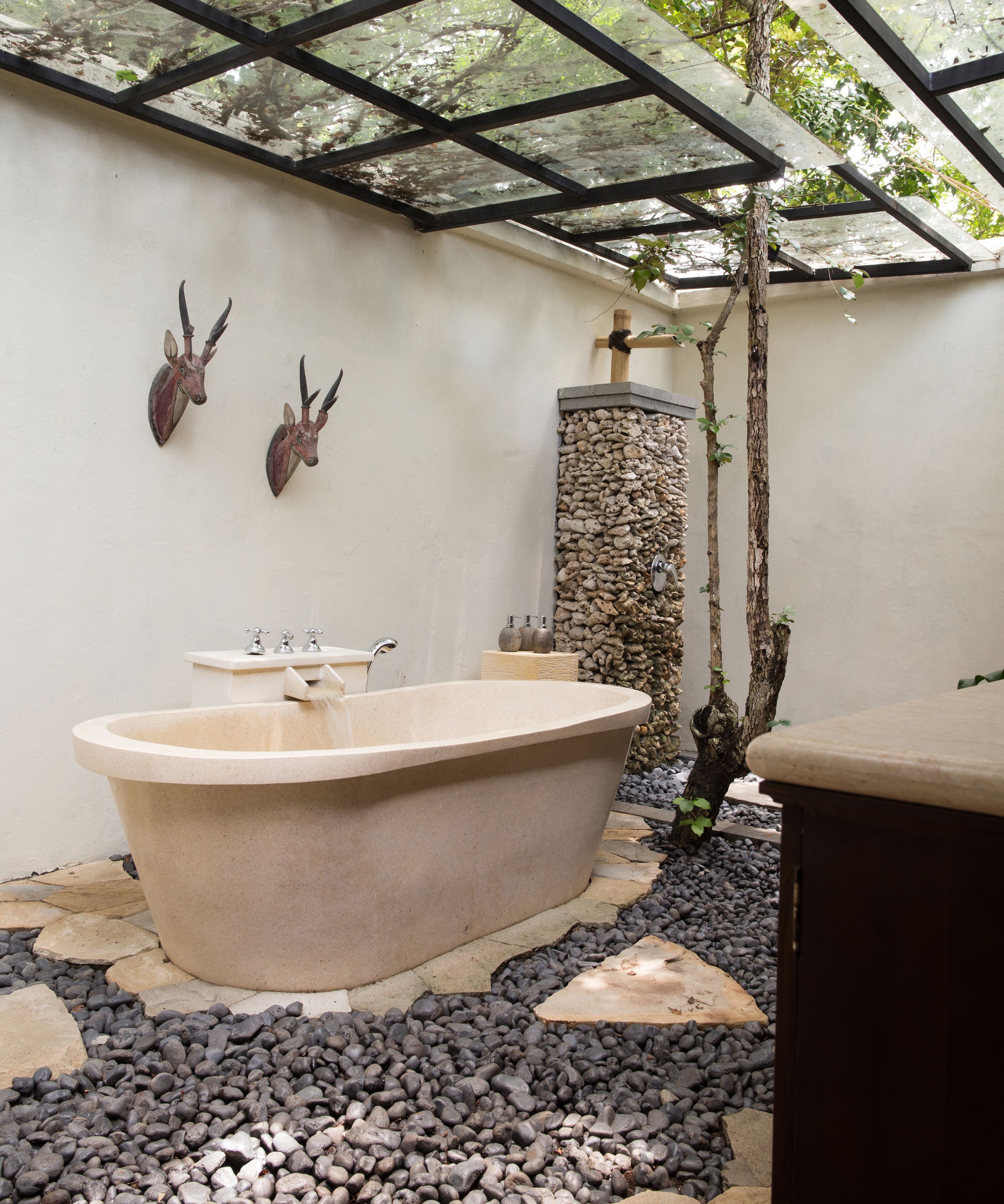 Un área de spa con una bañera independiente, una pared de piedra y dos venados montados en la pared.