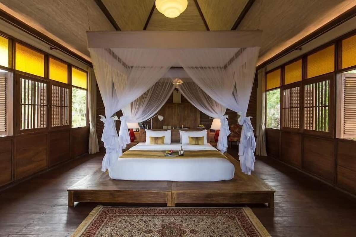 Une chambre traditionnelle avec un lit, des rideaux et un plancher en bois.