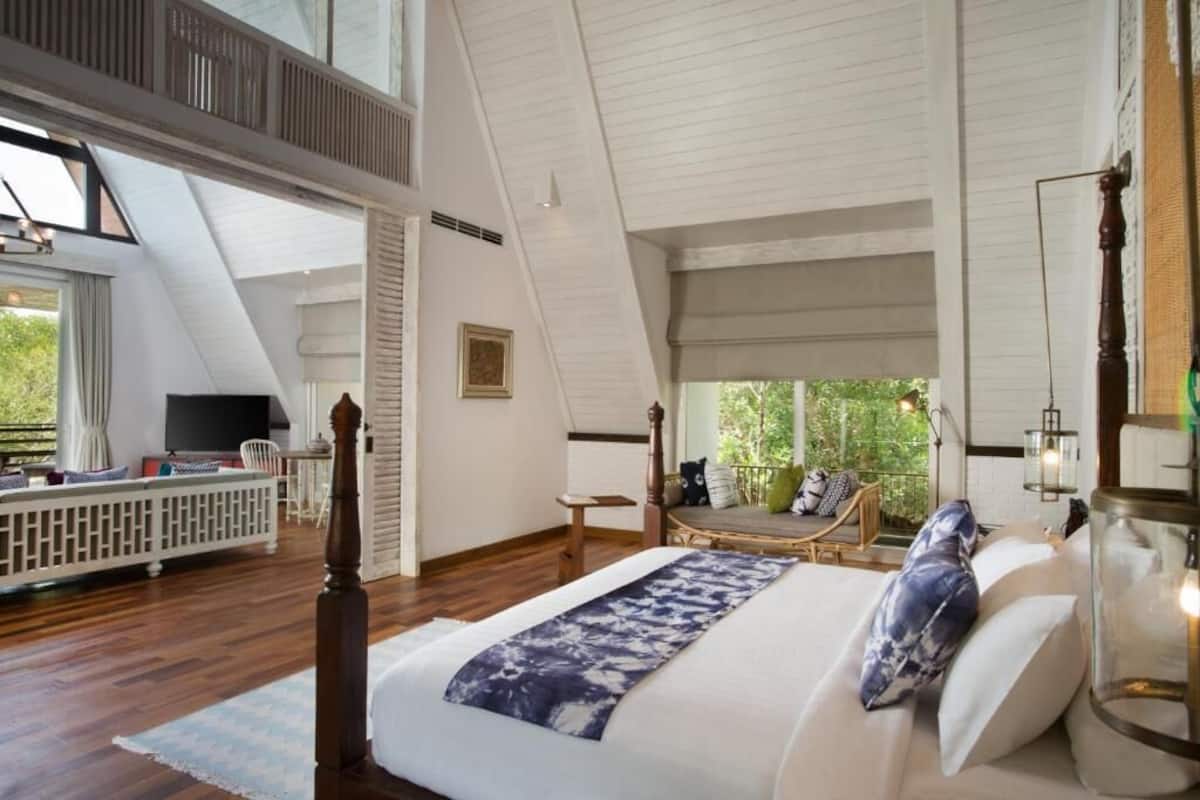 Une chambre spacieuse avec un grand lit, un plafond en bois et une vue sur la verdure environnante.