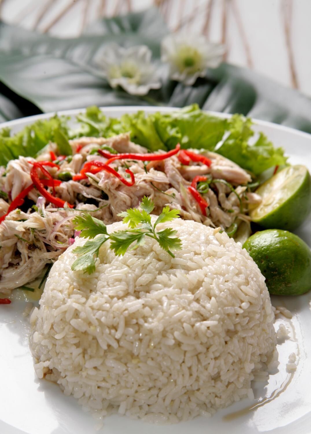 Un plato con arroz blanco, pollo desmenuzado y gajos de lima.
