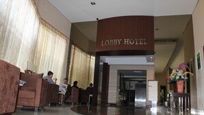 En lobby med receptionsdisk, siddeområde og et skilt der siger "Lobby Hotel".
