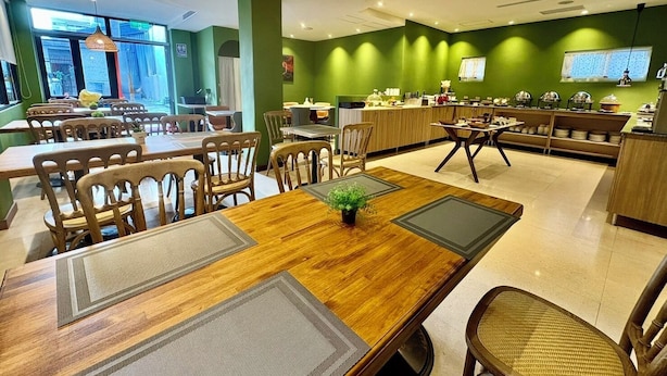 Un restaurante con mesas y sillas de madera, una zona de bufé y una pared verde con un panel de menú.