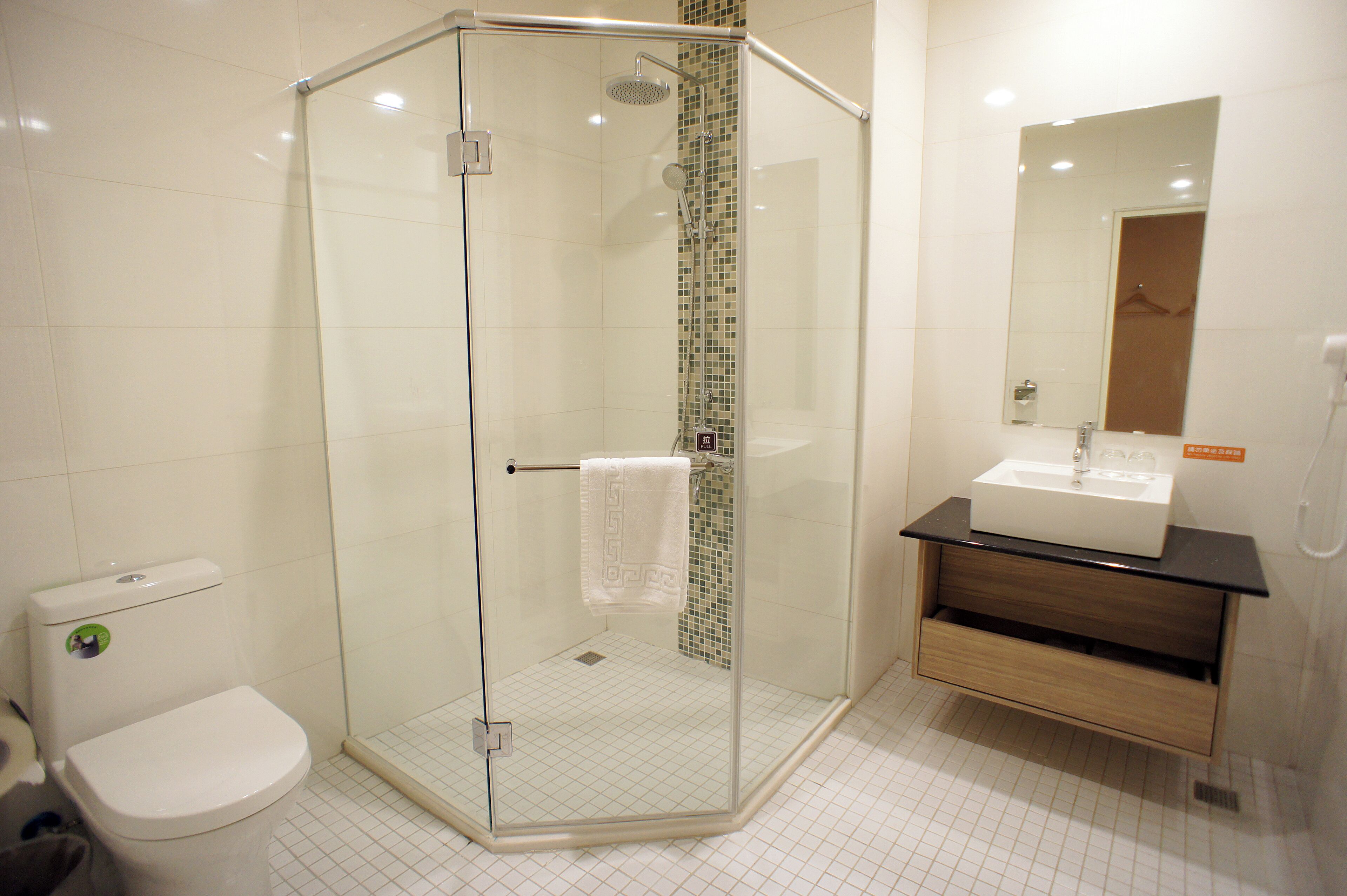 A modern bathroom with a glass-enclosed shower, a white toilet, and a wooden vanity with a sink.