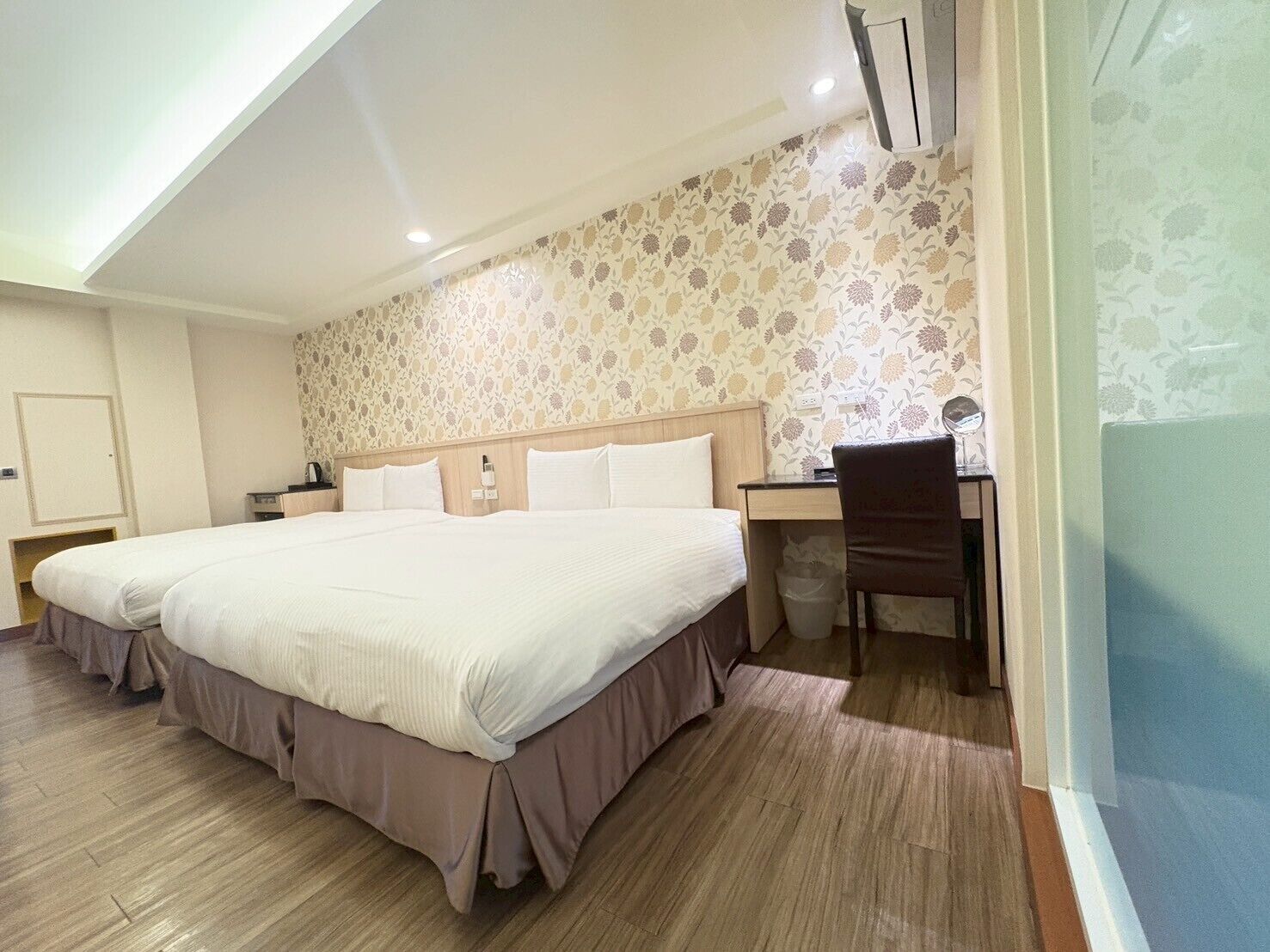 A hotel room with a large bed, a desk, and a chair.