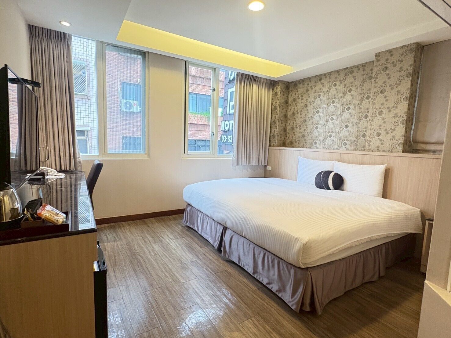 Una habitación de hotel con cama, un escritorio con teléfono y una ventana con cortinas.