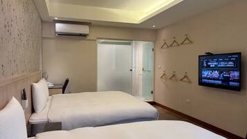 A hotel room with two beds, a TV mounted on the wall, and a door leading to a bathroom.