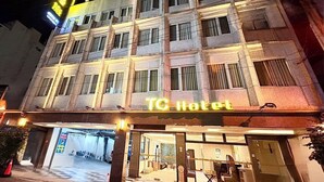 Un hotel con entrada a cuadros, una recepción visible y un cartel que indica que es un hotel TC.
