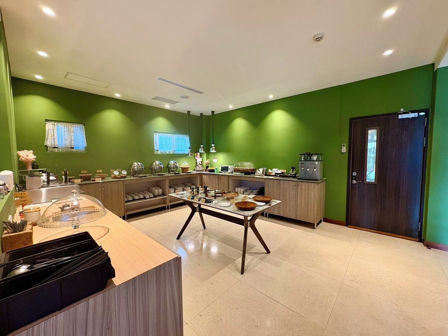 Una cocina moderna con paredes verdes, encimera de madera y una mesa de comedor con tazones.