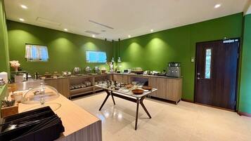 Una cocina moderna con paredes verdes, encimera de madera y una mesa de comedor con tazones.