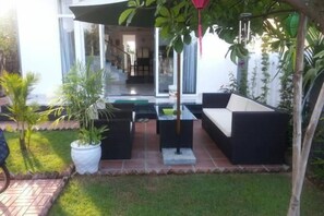Un espace extérieur aménagé avec un canapé, une table et des plantes en pot.