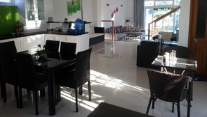 A modern kitchen with white cabinets, a dining area with black chairs, and a living room with a sofa and a coffee table. - Rice Field Homestay (Da Nang)
