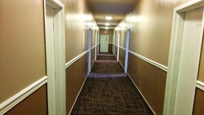 Un pasillo de hotel con pisos alfombrados y molduras blancas en las paredes.