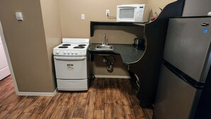 Una cocina compacta equipada con estufa, microondas, pileta y refrigerador.
